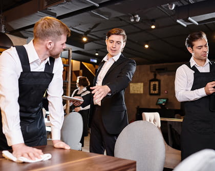 Restaurant manager coaching staff during table setup in a modern dining room